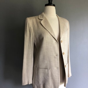 May include: A beige blazer with a striped pattern and two button fastenings. The blazer has a single pocket on the left side.