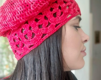 Pode incluir: Um gorro de crochê vermelho brilhante. O gorro apresenta um design vazado ao redor da aba e uma coroa texturizada e dobrada. Feito de fio macio, provavelmente lã ou algodão, é adequado para climas mais frios. Feito à mão.