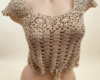 Pode incluir: Top de crochê bege feito à mão, com decote quadrado e mangas curtas. O top apresenta um delicado design vazado e um cordão na cintura. O top de crochê é exibido em um manequim.