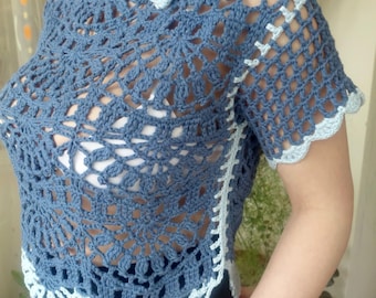 Pode incluir: Top de crochê azul com design floral. O top apresenta decote redondo e mangas curtas, com acabamento em azul claro. O trabalho de crochê é intrincado, criando um padrão aberto. Um pequeno adorno floral adorna o ombro.