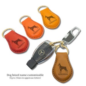 May include: Leather keyrings in red, orange, and brown, each with a Doberman silhouette and the breed name. The keyrings are attached to a car key and a metal clasp.