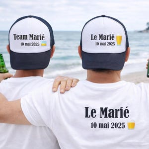 Peut inclure: Trois personnes portant des t-shirts blancs et des casquettes de baseball bleu marine et blanches sur une plage. Les casquettes indiquent "Team Marié" et "10 mai 2025". Les t-shirts ont "Le Marié" et "10 mai 2025" imprimés dessus. Chacun tient une bouteille verte.