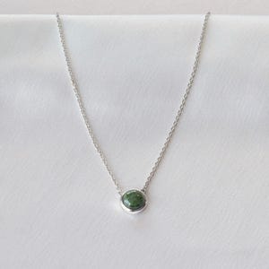 May include: A silver chain necklace with a green gemstone pendant.