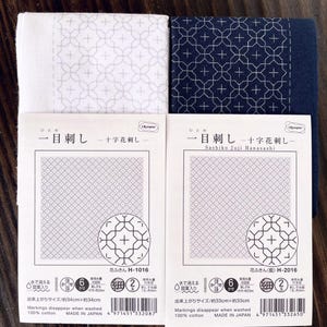 以下が含まれることがあります： 小さな十字の模様が印刷された白い布の正方形が2つ。布の正方形には「Sashiko Juji Hanasashi」と「H-1016」のラベルが貼られています。布の正方形は34cm×34cmで、100%綿製です。