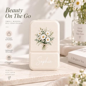 May include: A rectangular, cream-colored compact mirror featuring a printed bouquet of white daisies and green foliage on the top half, with the name Sophia written in white cursive script on the bottom half, presented in a clean, minimalist style.