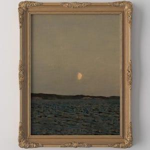 May include: A framed landscape painting depicts a serene seascape under a dusky sky. The artwork features a crescent moon, dark water, and a distant shoreline. The ornate gold frame adds a classic touch to the artwork.