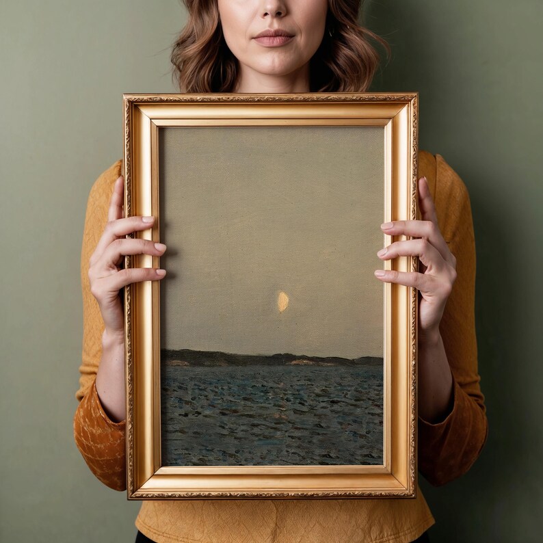May include: A framed landscape painting with a gold ornate frame. The artwork depicts a seascape with a pale yellow moon in a muted sky. The water is dark blue, and a dark land mass is visible in the distance.