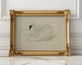 May include: A framed artwork featuring a watercolor painting of a white swan with a black beak and red accents. The artwork is set within an ornate, gold-colored frame, adding a touch of elegance. The frame is rectangular and has detailed carvings.