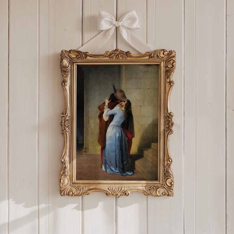 Pu&ograve; includere: Un dipinto incorniciato raffigurante una scena romantica di un uomo e una donna che si abbracciano. L'ornata cornice dorata &egrave; sospesa da un nastro bianco legato a fiocco. Il dipinto mostra una donna in abito blu e un uomo in cappotto marrone.
