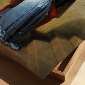 Pu&ograve; includere: Una stampa incorniciata di un dipinto raffigurante una figura drappeggiata in tessuto blu, con un accento rosso. L'opera d'arte &egrave; ambientata su uno sfondo di pavimento a motivi e una cornice di legno.