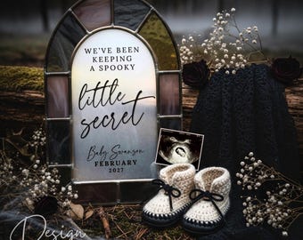 May include: A pregnancy announcement with a gothic theme. It features a stained-glass window with the text "We've been keeping a spooky little secret." There is a sonogram image and a pair of cream baby booties with black detailing. The scene is set against a dark, natural background.