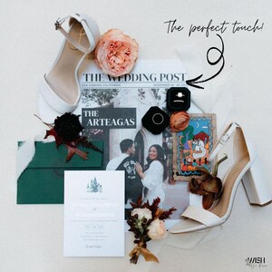 May include: A flat lay featuring wedding details. Includes white block-heeled sandals, a newspaper with the headline "THE WEDDING POST", a wedding invitation, and a small bouquet. The image also shows a ring box and a painting.