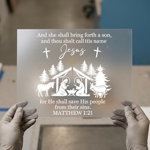 May include: A clear, rectangular glass panel with white text and a nativity scene illustration. The text reads "And she shall bring forth a son, and thou shalt call His name Jesus..." with a reference to Matthew 1:21.