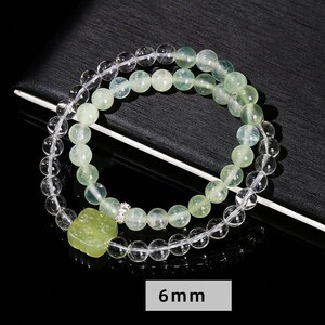 May include: A double-strand bracelet with clear and green beads. The bracelet has a square charm with a green stone.