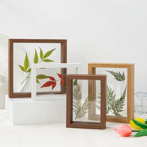 May include: Four different sized picture frames with wood frames and clear glass. The frames are empty and ready to be used to display pressed flowers or other small items.