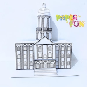 May include: A black and white paper model of a building with a domed tower. The building has multiple windows and a detailed facade. The words "PAPER FUN" are written in colorful letters.