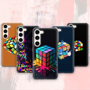 Può includere: Set di quattro custodie per telefono con disegni astratti colorati a tema cubo di Rubik. Le custodie sono nere, marroni, blu e bianche.