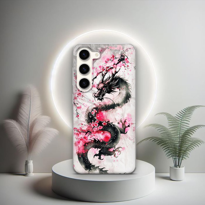 Puede incluir: Una funda transparente para tel&eacute;fono con un dise&ntilde;o de drag&oacute;n blanco y negro y flores de cerezo rosas. La funda tiene un recorte para la c&aacute;mara con tres lentes.
