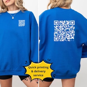 Op de afbeelding: Een koninklijk blauw sweatshirt met een witte QR-code gedrukt op de achterkant. Het sweatshirt heeft een ronde hals en lange mouwen.  "Snelle print & bezorgservice" staat in geel op een witte ster.