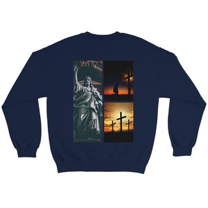 May include: Navy blue sweatshirt with a religious design. The design features a grayscale statue image and two images of crosses at sunset. The sweatshirt is made of a soft, comfortable material.