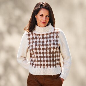 May include: A long-sleeve knit sweater featuring a cream-colored turtleneck and solid cream sleeves. The front panel displays a brown and cream houndstooth pattern. The sweater has a ribbed knit collar, cuffs, and hem, providing a textured finish.