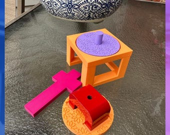 May include: A set of geometric plastic objects including an orange square frame with a purple circular insert featuring a floral pattern, a bright pink cross-shaped piece, and a red arch-shaped block on an orange circular base with floral details.