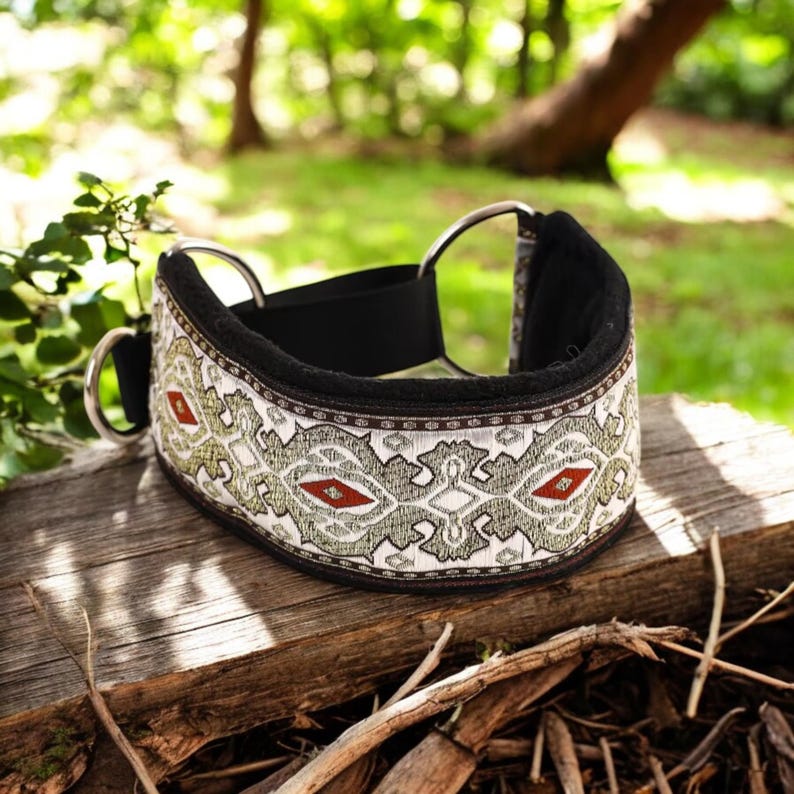 Puede incluir: Un collar de perro blanco y negro con un borde de patr&oacute;n verde y rojo. El collar est&aacute; hecho de un material suave y acolchado y tiene dos anillos en D de metal.