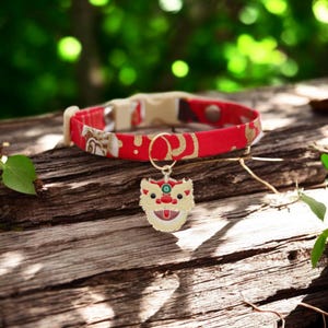 May include: Red and gold patterned fabric cat collar with a gold lion's head charm.