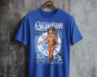 Może przedstawiać: Niebieski T-shirt z grafiką w stylu vintage przedstawiającą osobę w futurystycznym kombinezonie i plecakiem. Grafika zawiera napis "Quantum Tunneling Device" i "Best One Today".