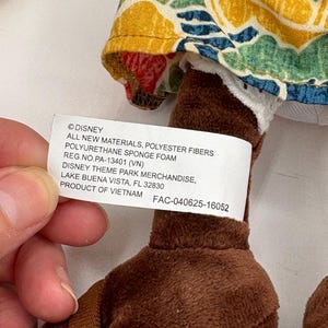 May include: A plush toy with brown legs and a floral patterned fabric. The tag reads "&copy;DISNEY" and "DISNEY THEME PARK MERCHANDISE, LAKE BUENA VISTA, FL 32830". The toy is made of polyester fibers and polyurethane sponge foam.