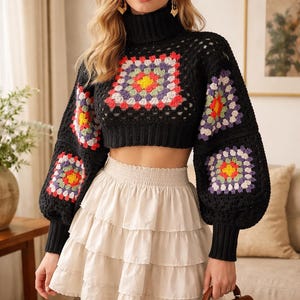 Peut inclure: Pull court en crochet noir avec des motifs carrés colorés sur le devant et les manches. Associé à une mini-jupe à volants crème. Un sac à main marron avec une boucle dorée est tenu à la main.