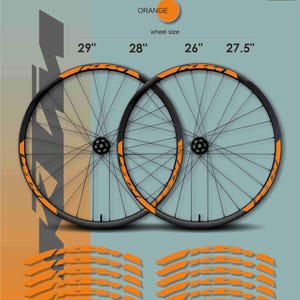 Peut inclure: Deux roues de vélo noires avec des détails orange, avec des tailles de 29", 28", 26" et 27,5". L'image comprend également des autocollants orange et le texte "ORANGE" et "wheel size". Le logo "MAX MODEL STUDIO" est en haut à droite.
