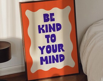 Könnte beinhalten: Ein gerahmter Druck mit orangefarbenem Hintergrund und einer weißen, wellenförmigen Umrandung. Der Text "Be Kind To Your Mind" ist in lila Buchstaben.