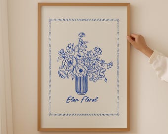May include: A framed floral art print featuring a blue and white illustration of a bouquet in a striped vase. The artwork is labeled "Élan Floral" in blue script and is set against a cream-colored background.