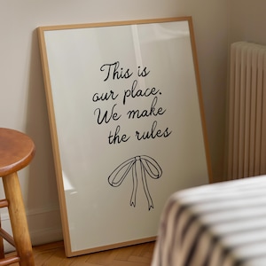 Może przedstawiać: Wydruk w ramie z tekstem "This is our place. We make the rules" i ilustracją czarnej kokardki.