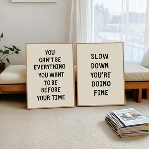 May include: Two framed art prints with inspirational quotes. The left print reads "YOU CAN'T BE EVERYTHING YOU WANT TO BE BEFORE YOUR TIME." The right print says "SLOW DOWN YOU'RE DOING FINE."