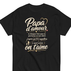 Peut inclure: T-shirt noir avec l'inscription "Papa d'amour" en écriture cursive, avec du texte supplémentaire en dessous. Le motif comprend de petits cœurs et étoiles. Le t-shirt est à col rond et à manches courtes.