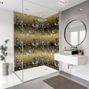 May include: A modern bathroom with a glass shower enclosure featuring a gold and green peacock patterned shower curtain. The shower has a white tiled floor and a white ceiling. The bathroom also has a white vanity with a round mirror and a white sink.