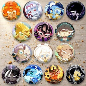 Pode incluir: Uma coleção de doze botões redondos e coloridos com personagens. Cada botão apresenta um personagem de desenho animado diferente com designs e esquemas de cores únicos, incluindo laranja, branco, azul e preto. Os botões estão dispostos em uma superfície marrom claro.