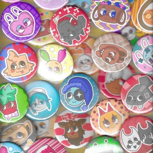 Può includere: Una collezione di bottoni rotondi e colorati con vari disegni di personaggi dei cartoni animati. I bottoni presentano una varietà di colori, tra cui rosa, blu, verde e rosso, con illustrazioni fantasiose di animali e altre figure carine.