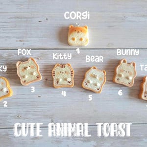 Puede incluir: Una colecci&oacute;n de lindos amuletos de tostadas de animales, que incluyen un corgi, un zorro, un gatito, un oso, un conejito, un patito y un zorro marr&oacute;n. Cada amuleto est&aacute; dise&ntilde;ado para parecerse a una rebanada de tostada con una cara de animal. El texto "CUTE ANIMAL TOAST" tambi&eacute;n es visible.