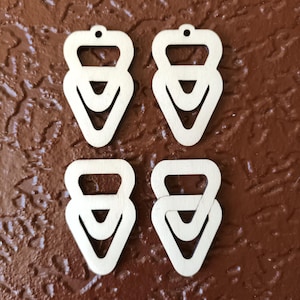 May include: Four unfinished wooden triangle shapes with a hole at the top. The triangles are layered on top of each other to create a geometric design.