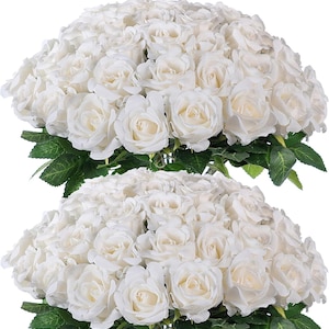 May include: Two bouquets of white roses with green leaves. The roses are in full bloom, with multiple petals. The leaves are a deep green color. The bouquets are arranged in a dense, rounded shape.