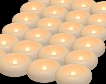Pode incluir: Uma coleção de velas de chá LED de cor marfim. Cada vela tem uma luz quente e trêmula, criando um brilho suave e convidativo. As velas estão dispostas em diagonal sobre um fundo preto.