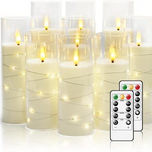 以下が含まれることがあります： 透明なガラスシリンダーに入った、アイボリー色のLEDピラーキャンドルのコレクション。各キャンドルはちらつき炎効果があり、ストリングライトで包まれています。2つのリモコンが含まれています。