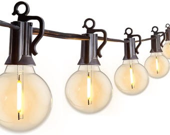 May include: String of outdoor globe lights with warm, yellow illumination. Each bulb is round and clear, suspended from a dark brown wire with decorative metal fixtures. The lights are ideal for patios and outdoor spaces.