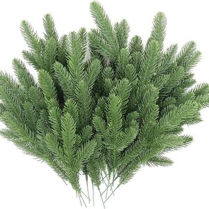 May include: A bundle of artificial evergreen branches with a realistic appearance. The green needles are densely packed on the stems, creating a full and textured look. The stems are thin and wire-like, suitable for floral arrangements or holiday decorations.