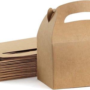 Puede incluir: Una pila de cajas de cartón marrones planas y sin plegar junto a una sola caja ensamblada con asa. La caja ensamblada es rectangular con una parte superior y un asa curvadas. Las cajas están hechas de cartón marrón claro sin recubrimiento.