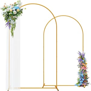 Puede incluir: Arco de boda de metal dorado con dos arcos conectados. Un arco está decorado con una cascada de flores coloridas, incluyendo flores azules, blancas y moradas. El otro arco también está decorado con flores. Una tela blanca transparente está unida al arco izquierdo.