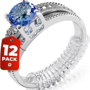 Puede incluir: Un anillo plateado con una gran piedra preciosa azul ovalada y piedras claras más pequeñas. Una etiqueta roja con el texto "12 PACK" está adjunta. Un ajustador de anillo en espiral transparente está envuelto alrededor de la banda.